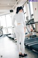 A woman standing in front of a row of treadmills in a gym.