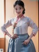 A woman in a blue and white hanbok poses for a picture.