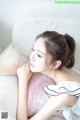 A woman laying on top of a white couch next to a pink pillow.