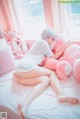 A woman laying on a bed with pink stuffed animals.