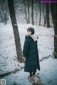 A woman standing in the snow in a park.