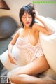 A woman in a white lingerie sitting on a bed.