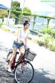 A woman riding a bike with a basket on the back.