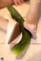 A person cutting up a cucumber on a cutting board.