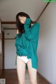 A woman in a green sweater and white panties posing for a picture.