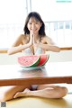 A woman sitting at a table with a plate of watermelon.