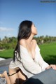 A woman sitting on top of a wooden bench next to a pool.