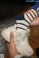 A person holding a pair of white sneakers with blue and white socks.