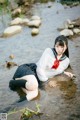 A woman in a school uniform is sitting in the water.