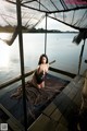 A woman sitting on a dock next to a body of water.