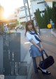 A woman in a school uniform is standing on the street.