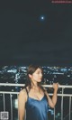 A woman in a blue dress standing on a balcony at night.