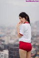 A woman in a white shirt and red shorts posing for a picture.