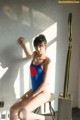 A woman in a blue and red bathing suit sitting on a stool.