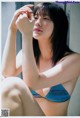 A woman in a blue bikini sitting on a window sill.