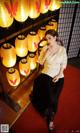 A woman sitting on a chair in front of a bunch of paper lanterns.