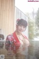 A woman in a red kimono is standing in the water.
