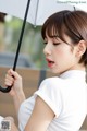 A woman in a white shirt holding an umbrella.