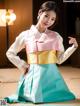 A woman in a blue and pink hanbok is posing for a picture.