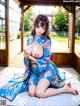 A woman in a blue kimono sitting on a bed.