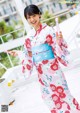 A woman in a kimono blowing bubbles on a balcony.