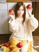 A woman sitting on the floor holding two apples in her hands.